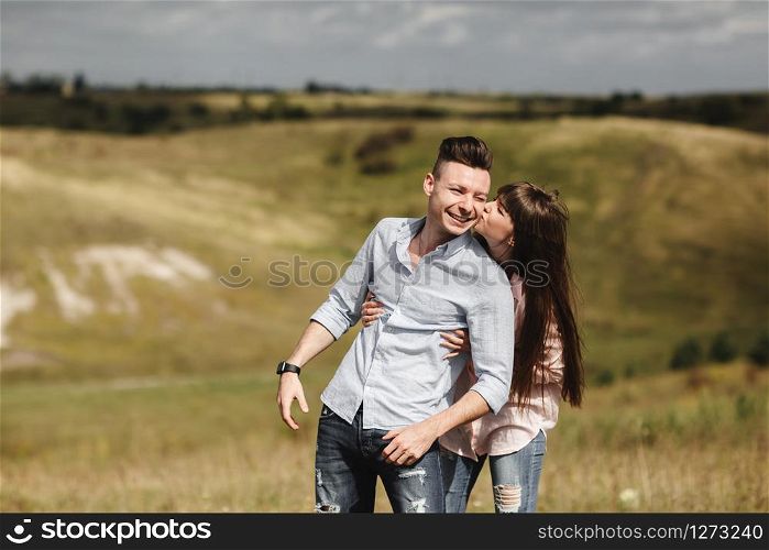 Young couple outdoor portrait. Beautiful pretty girl kissing handsome boy. Sensual photo. young stylish fashion couple kissing in summer in corn field behind rainy clouds and storm.. Young couple outdoor portrait. Beautiful pretty girl kissing handsome boy. Sensual photo.