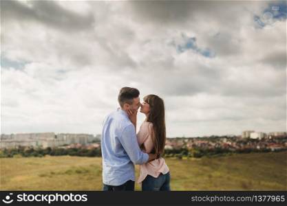 Young couple outdoor portrait. Beautiful pretty girl kissing handsome boy. Sensual photo. young stylish fashion couple kissing in summer in corn field behind rainy clouds and storm.. Young couple outdoor portrait. Beautiful pretty girl kissing handsome boy. Sensual photo.