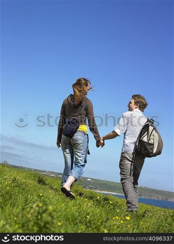 Young couple outdoors holding hands.