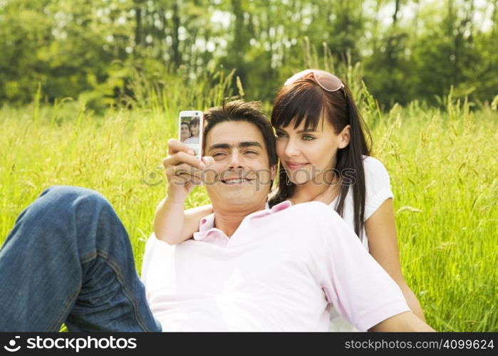 Young couple outdoors, woman taking photo with mobile phone