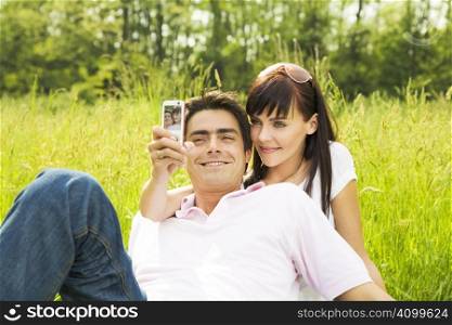 Young couple outdoors, woman taking photo with mobile phone