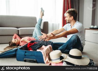 Young couple packing their suitcases for vacation. Fees on journey concept. Luggage preparation. Young couple packing their suitcases for vacation