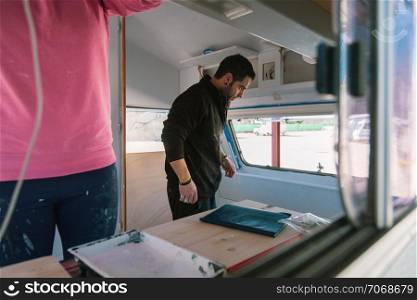 Young couple painting and restoring caravan