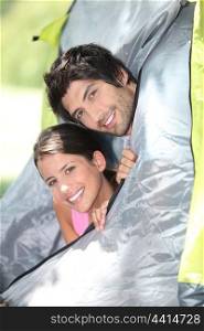 Young couple peeking out of their tent
