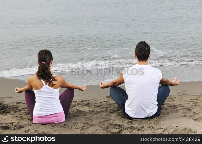 young couple people meditating yoga in lotus position at early morning on the beach