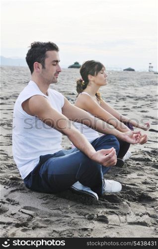 young couple people meditating yoga in lotus position at early morning on the beach