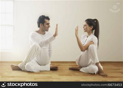 Young couple performing yoga face to face