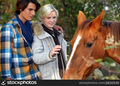 Young couple petting horse