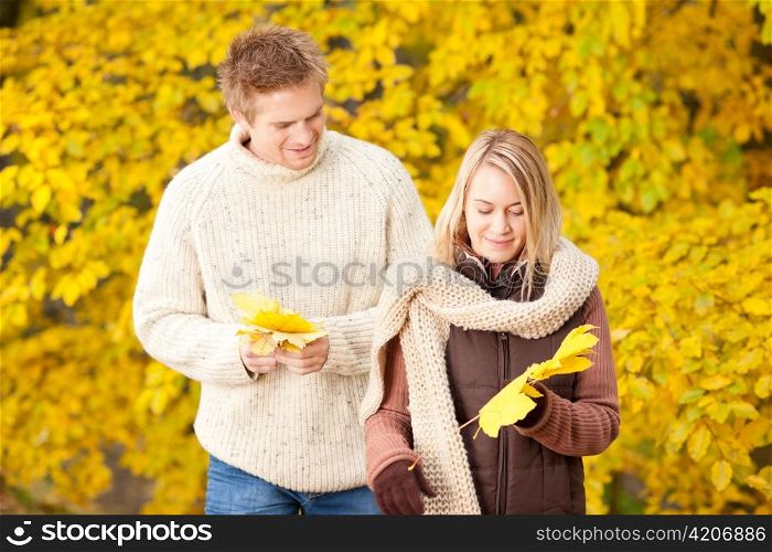 Young couple picking leaves in autumn park outfit