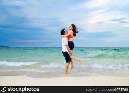 young couple picking up and hugging on the sea beach at Koh MunNork Island, Rayong, Thailand