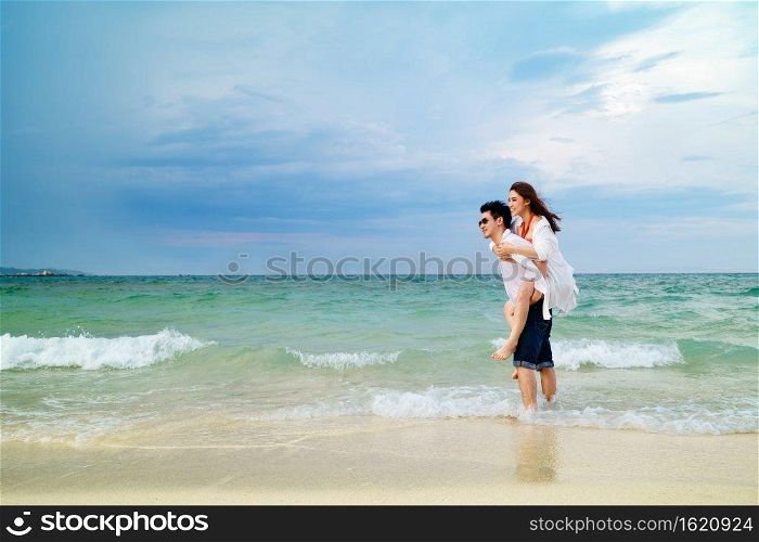 young couple piggyback ride on the sea beach at Koh MunNork Island, Rayong, Thailand