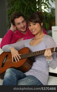 Young couple playing a guitar at home