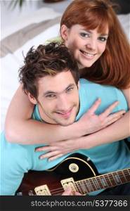Young couple playing a guitar at home