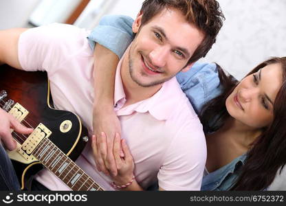 Young couple playing a guitar at home