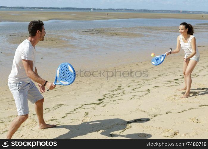 young couple playing beach tennis