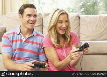 Young Couple Playing Computer Game On Sofa At Home