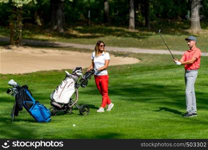 Young couple playing golf on a beautiful summer day