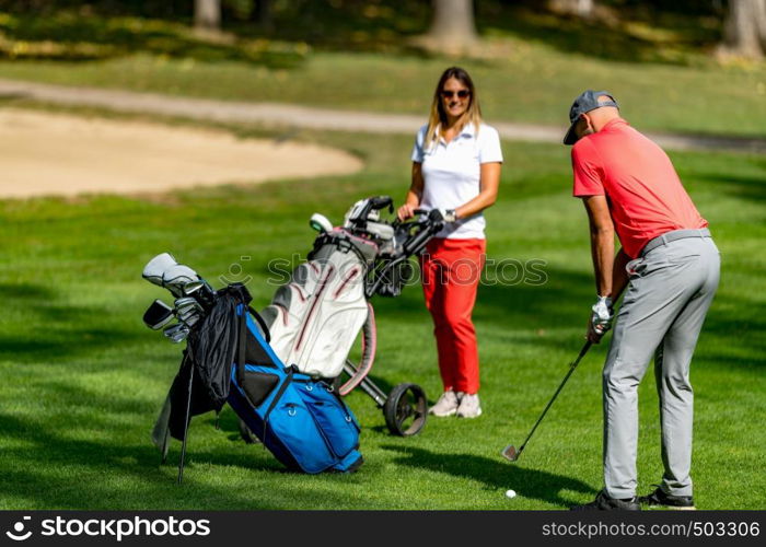 Young couple playing golf on a beautiful summer day