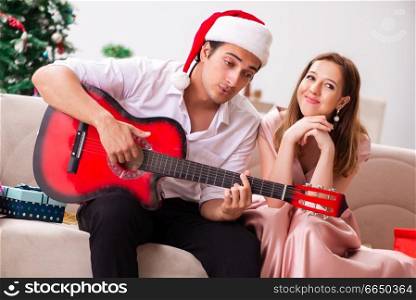 Young couple playing guitar at christmas