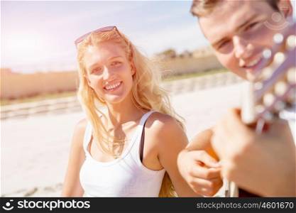 Young couple playing guitar on beach in love. Happy romantic young couple playing guitar on beach in love