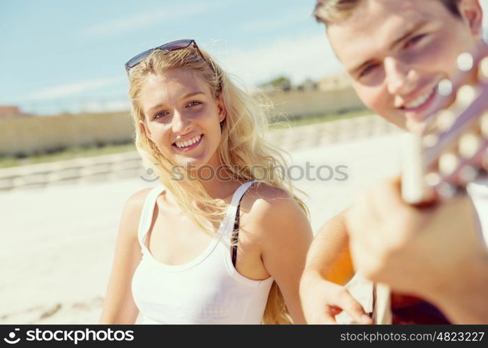 Young couple playing guitar on beach in love. Happy romantic young couple playing guitar on beach in love