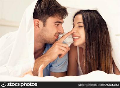 Young couple playing under the sheets