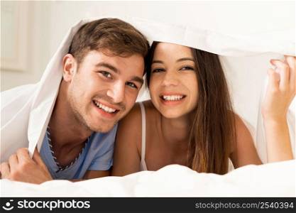 Young couple playing under the sheets