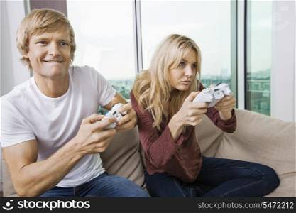 Young couple playing video game in living room at home
