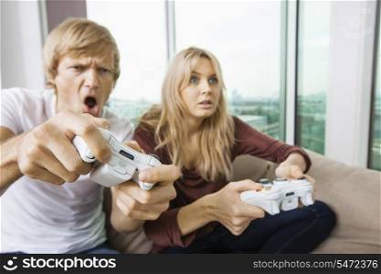 Young couple playing video game in living room at home