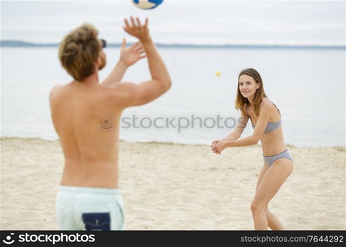 young couple playing volley ball on the beach