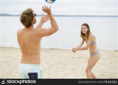 young couple playing volley ball on the beach