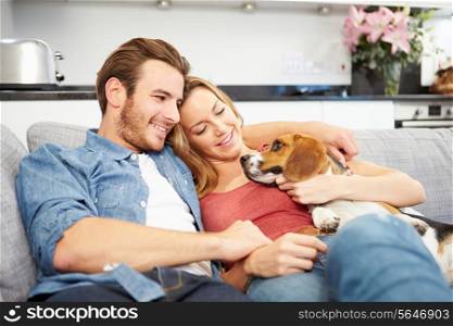Young Couple Playing With Pet Dog At Home