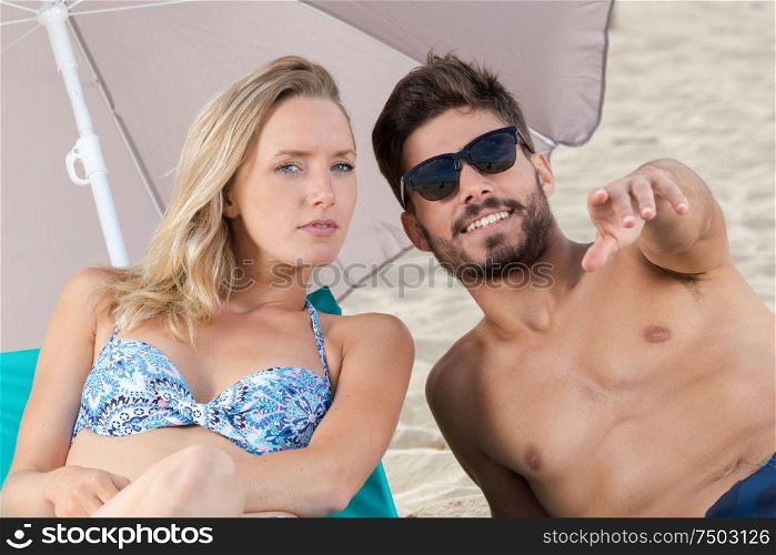 young couple pointing at something on the beach