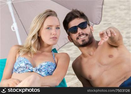 young couple pointing at something on the beach