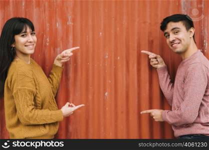 young couple pointing orange fence