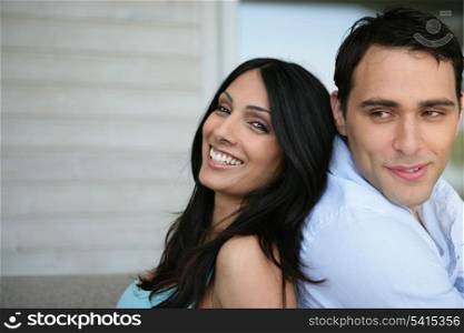 young couple posing outdoors back to back
