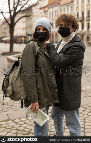 young couple posing outdoors with medical masks