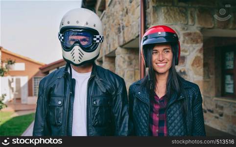 Young couple posing with motorcycle helmets outdoors. Couple posing with motorcycle helmets