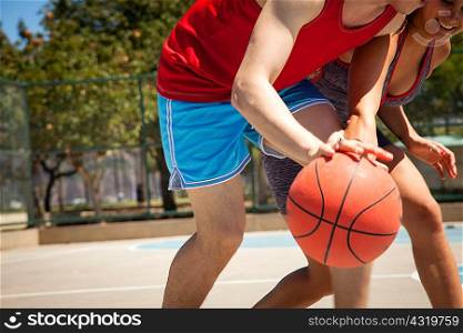 Young couple practicing basketball on court