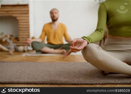 Young couple practicing meditation sitting in lotus position. Morning yoga in pair, mindfulness exercise for wellness and relaxation. Young couple practicing meditation sitting in lotus position