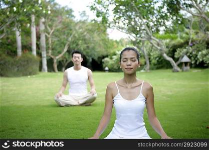 Young couple practising yoga outdoors