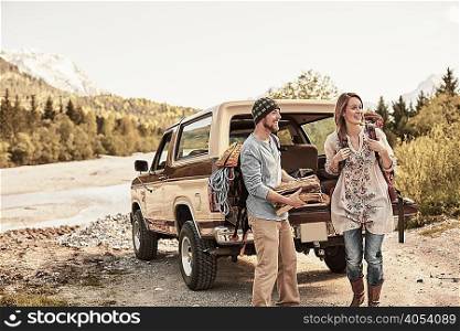 Young couple preparing to go hiking, carrying firewood