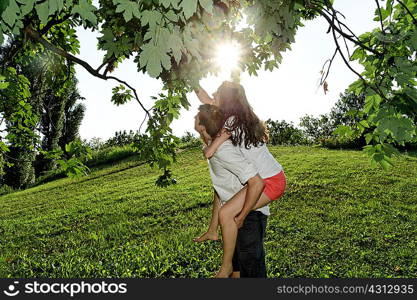 Young couple reaching up to tree branches