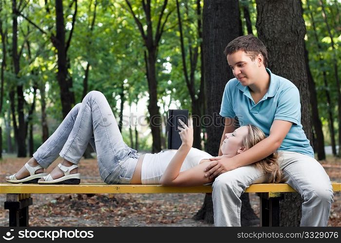 young couple reading book in the park