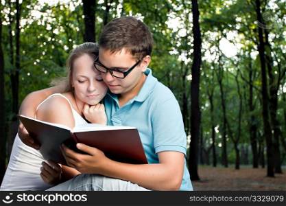 young couple reading book in the park
