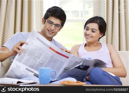 Young couple reading newspaper together
