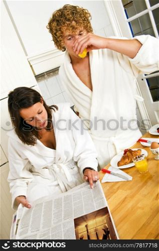 Young couple reading the paper on a casual morning breakfast in the kitchen
