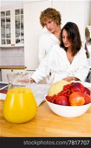 Young couple reading the paper whilst enjoying a healty breakfast, dressed in bathrobes