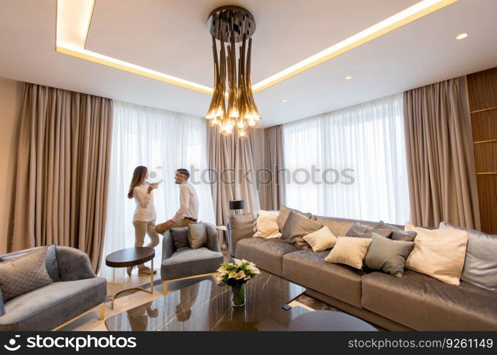 Young couple relaxing and talking with coffee cups in the luxurious room of contemporary apartment