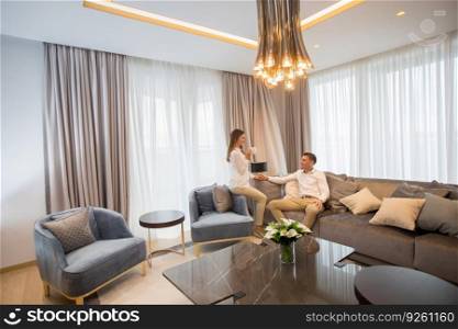 Young couple relaxing and talking with coffee cups in the luxurious room of contemporary apartment
